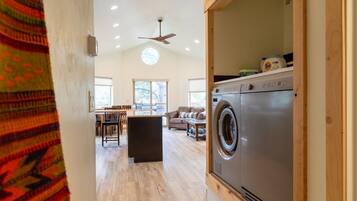 A spacious living area with a washing machine, a ceiling fan, and a dining area with chairs and a table.