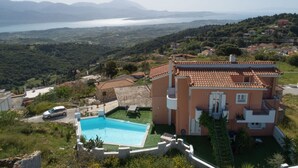 Una villa con piscina, rodeada de vegetación exuberante y vista al mar.