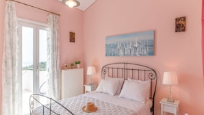Un dormitorio con cama, mesitas de noche, un radiador, una ventana con cortinas y un cuadro en la pared.