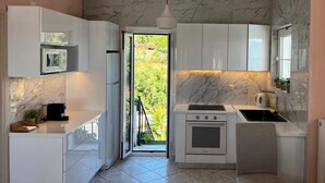 Una cocina compacta con gabinetes blancos, horno empotrado y un lavamanos.