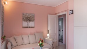 Una sala de estar con un sofá color crema, una mesa de centro de vidrio y un cuadro de árboles en la pared.