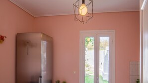 Una cocina compacta con refrigerador, una mesa de comedor con sillas y una ventana con vistas a un jardín.