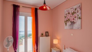 Un dormitorio con cama, mesita de noche, lámpara, ventilador y un cuadro en la pared.