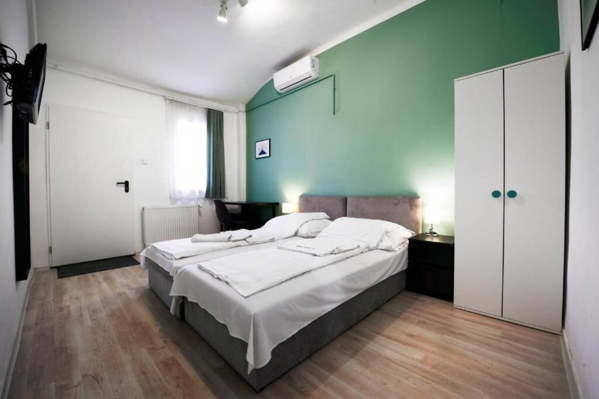 A bedroom with a double bed, a wardrobe, a desk, and a radiator.