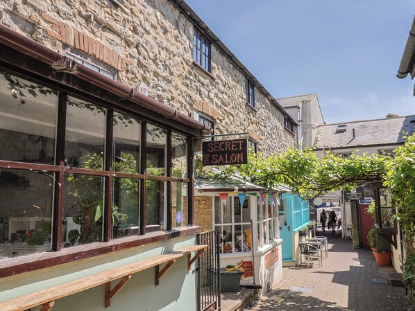Un bâtiment en pierre avec une enseigne indiquant « Salon secret », une petite boutique vendant des ours en peluche et une porte bleue.