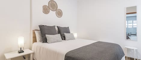 A neatly arranged bedroom with a bed, bedside tables, and a mirror.