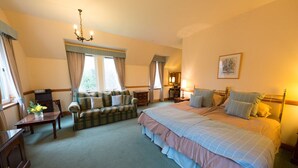 Une chambre d’hôtel avec un grand lit, un canapé, un bureau et un lustre.