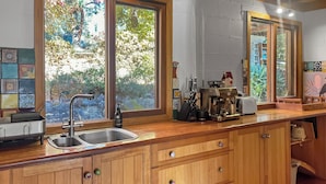 Een keuken met houten kastjes, een roestvrijstalen spoelbak en een koffiezetapparaat.