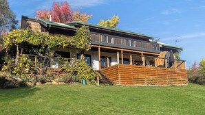 Een huis met twee verdiepingen, een houten terras en een gevel van natuursteen.