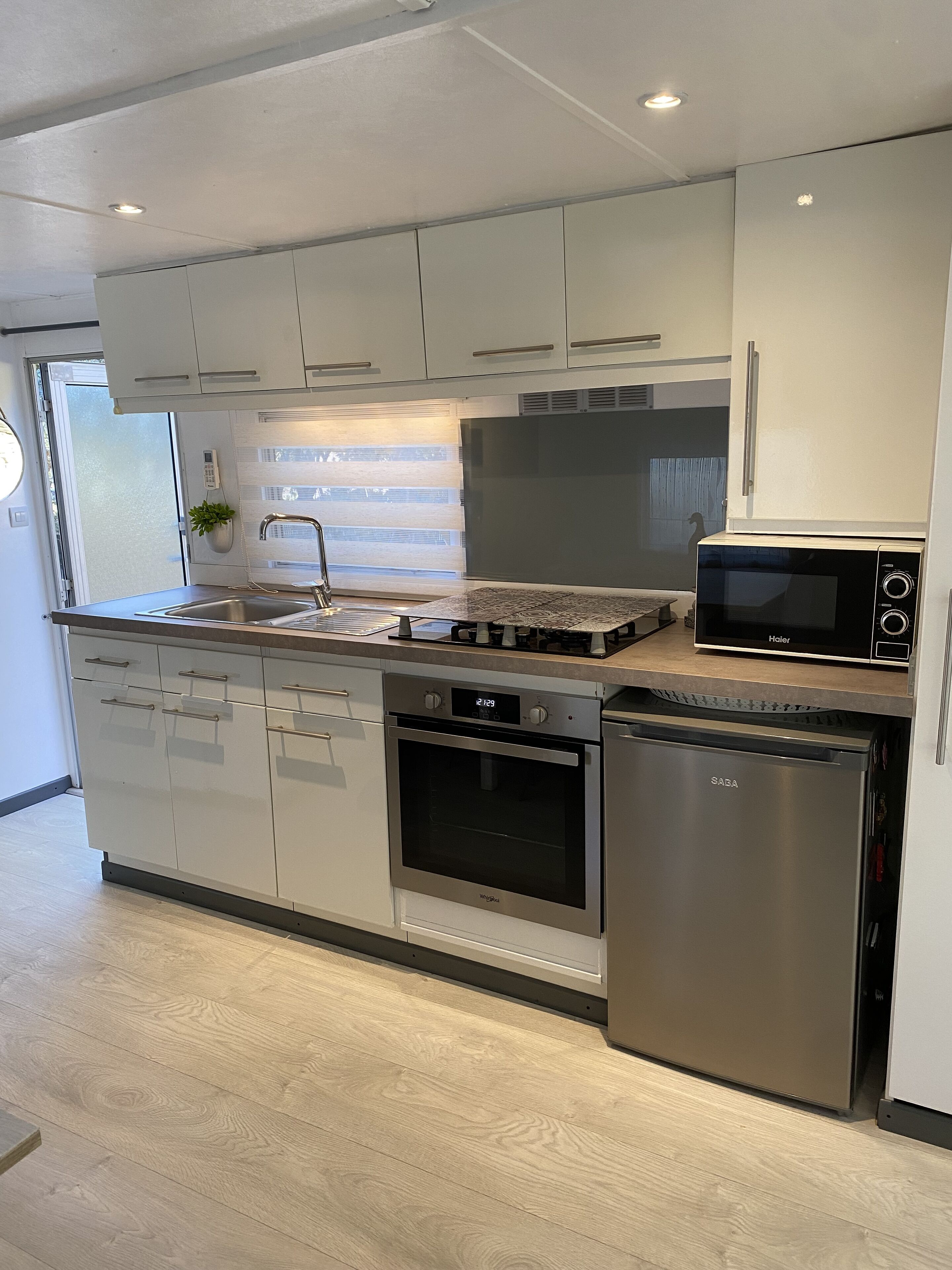 Una cocina moderna con electrodomésticos de acero inoxidable, incluyendo un microondas, horno y lavavajillas.