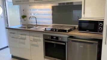 Una cocina moderna con electrodomésticos de acero inoxidable, incluyendo un microondas, horno y lavavajillas.