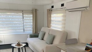 Ein modernes Wohnzimmer mit einer Couch, einem kleinen runden Tisch und einem Esstisch mit Stühlen.