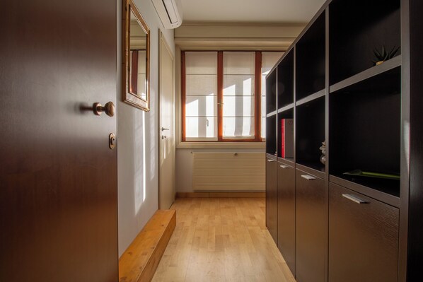 Un pasillo con piso de madera, un radiador y una puerta con espejo.