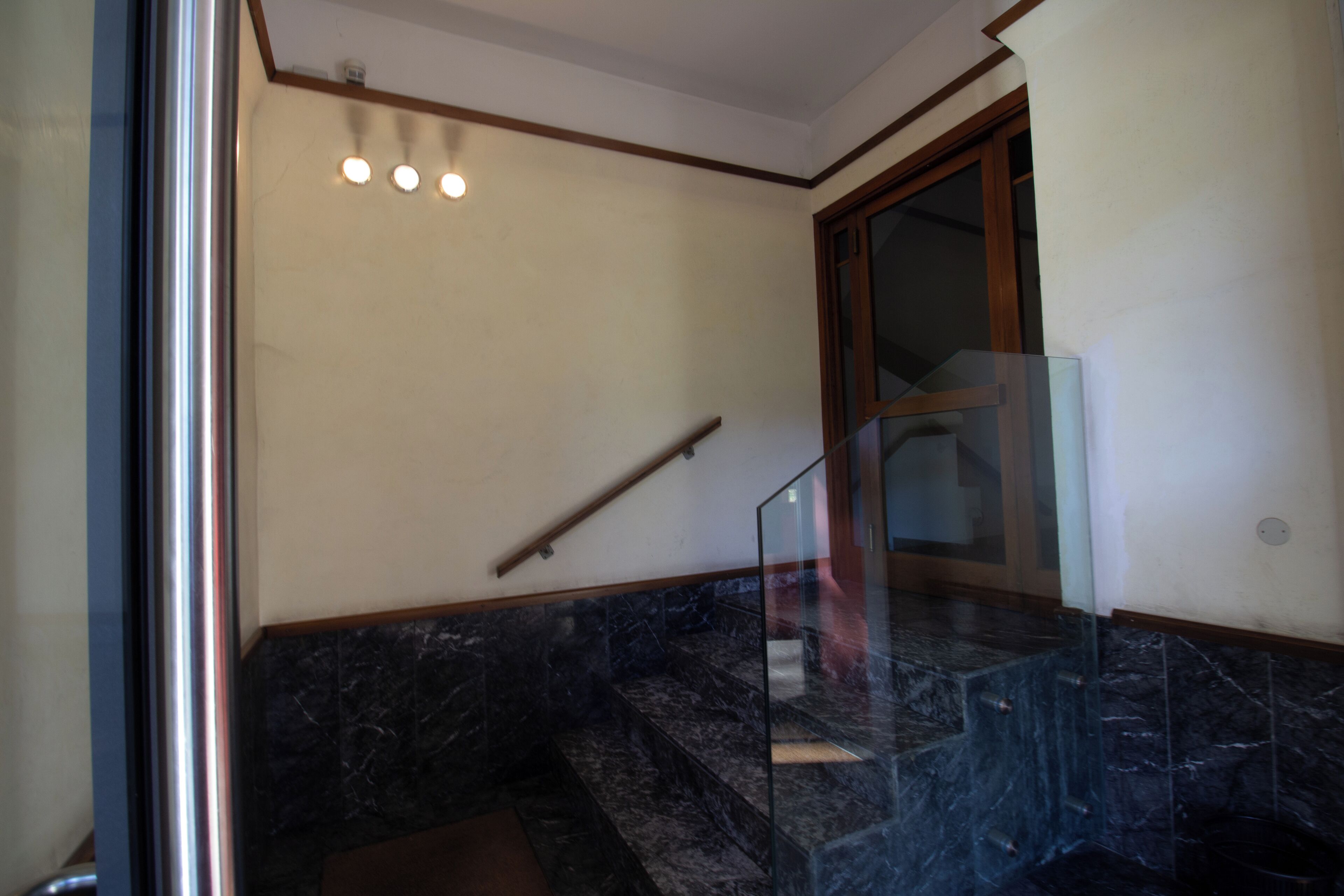 A staircase with marble steps and a glass railing.