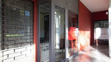 Un edificio moderno con puerta de entrada de vidrio, buzón rojo y suelo de baldosas.