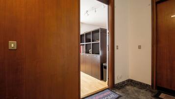 Entrada de hotel con puerta de madera, felpudo y vista a una habitación con kitchenette.