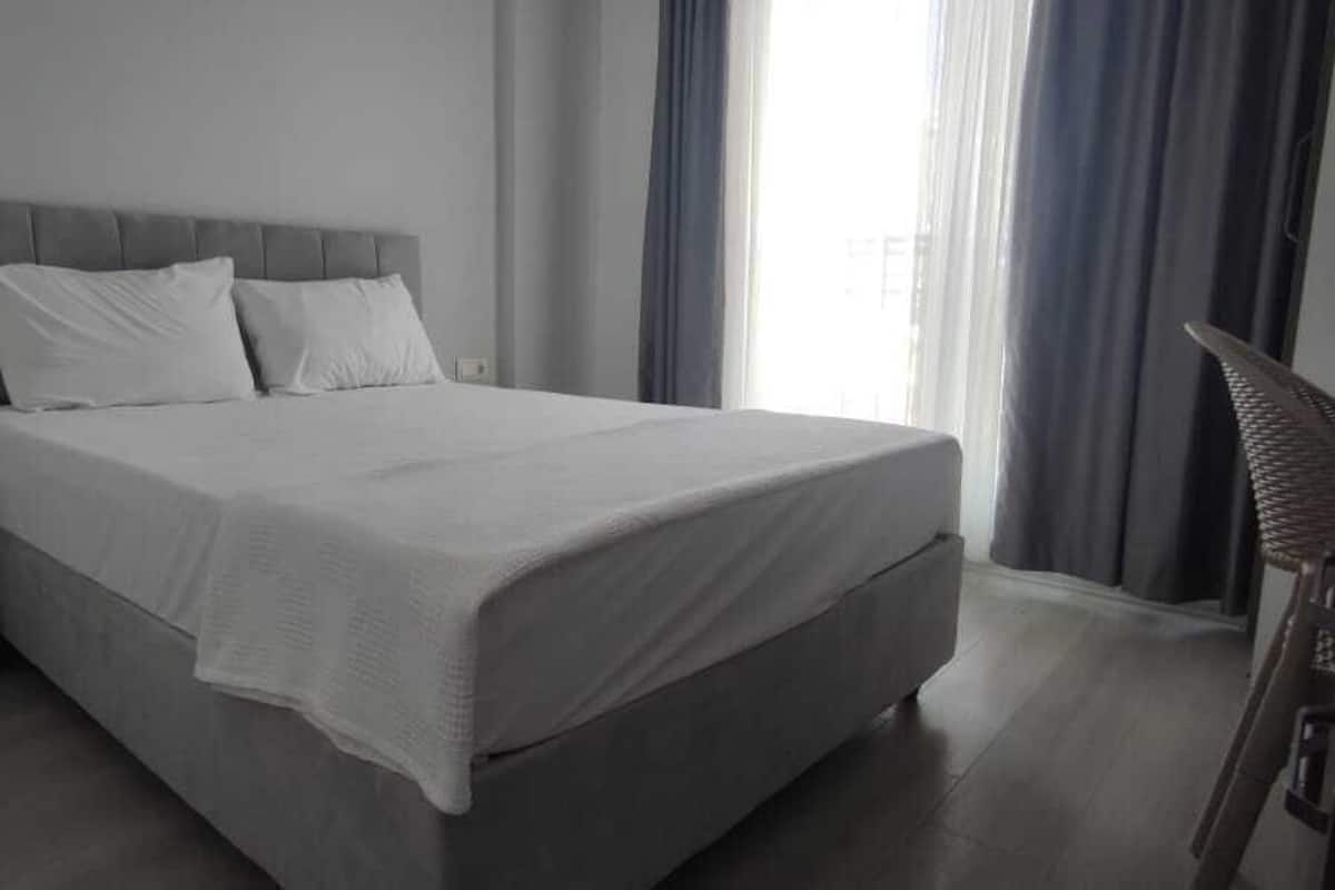 A modern bedroom with a large bed, a bedside table, and a nightstand.