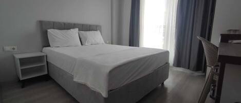 Un dormitorio moderno con una cama grande, una mesita de noche y una mesita auxiliar.