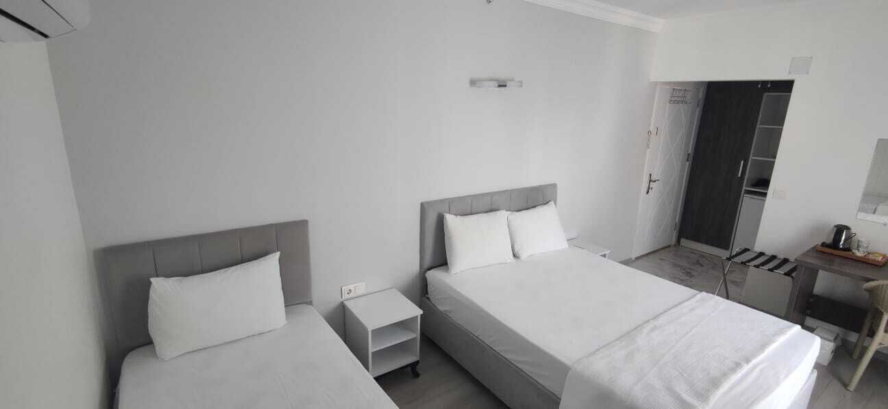 A modern hotel room with two single beds, a small desk, and a walk-in closet.