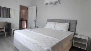 A hotel room with a large bed, a desk with a chair, a wardrobe, and a mirror. - Aykaç Otel Susanoğlu (Silifke)