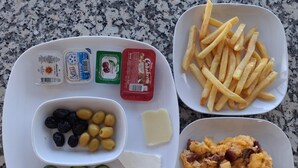 A meal tray with French fries, scrambled eggs, a salad with cucumbers and tomatoes, olives, and cheese. - Aykaç Otel Susanoğlu (Silifke)