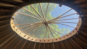 Een ronde houten constructie met een centrale houten paal en gelijkmatig verdeelde houten latten eromheen.