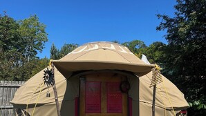 Een tent met een houten deur en een kleurrijk interieur.