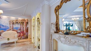 A luxurious room with a white sofa, a decorative wall mural, a large ornate mirror, and a marble floor. - Marino Mar | Boutique Apartment | Spa & Wellness, pools, sun loungers included (Sunny Beach)