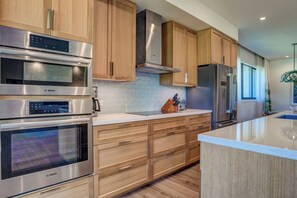 Una cocina moderna con electrodomésticos de acero inoxidable, armarios de madera y una isla grande.
