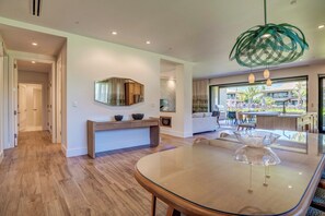 Et moderne spiseområde med et glasbord, et konsolbord med dekorative genstande og udsigt til terrassen.