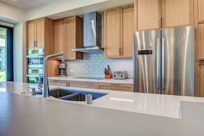 Una cocina moderna con electrodomésticos de acero inoxidable, armarios de madera y una isla grande con un lavamanos.