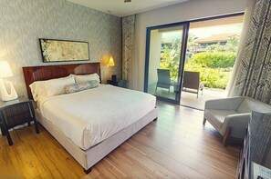Habitación de hotel con una cama grande, un escritorio, una silla, una mesita de noche y vistas al exterior.