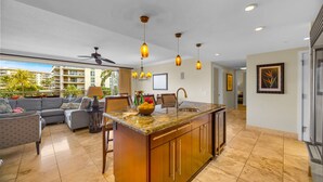 A spacious kitchen with a central island, pendant lighting, and a view of a residential area. - Honua Kai | Ocean View 6 BR, Sleeps 16 | Car Incl. w/ 6+ Nights | HKH ML-1097 by KBM (Lahaina)