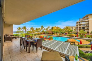 Ein Balkon mit Tisch und Stühlen, mit Blick auf einen Pool und die Gebäude des Resorts.