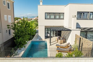Ein modernes Haus mit Swimmingpool, Sitzgelegenheit im Freien und Blick auf die Stadt.