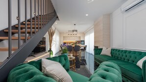 A modern living room with a green sofa, a staircase, and a kitchen in the background. - Villa Mia Zadar Villas (Privlaka)