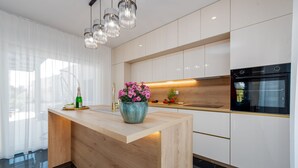 A modern kitchen with a wooden island, stainless steel appliances, and a large window with sheer curtains. - Villa Mia Zadar Villas (Privlaka)