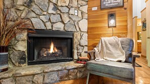 A stone fireplace with a fire, a chair with a blanket, and a sign for Great Smoky Mountains National Park.