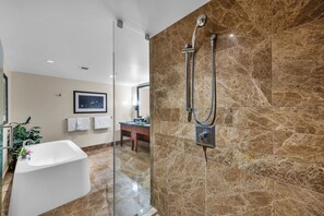 Ein modernes Badezimmer mit einer gläsernen Duschkabine, einer freistehenden Badewanne und einem Waschtisch mit Spiegel.