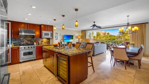A modern kitchen with a central island, stainless steel appliances, and a dining area with a view.