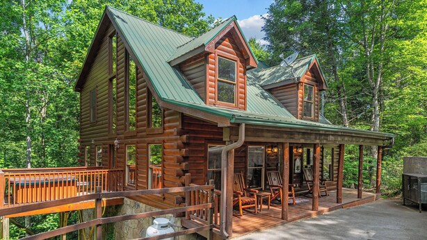 A log cabin with a porch, a deck, and a stone foundation. - A Home For The Whole Family, Even The Family Dog (GATLINBURG)