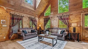 A cozy log cabin interior with two leather sofas, a central coffee table, and patterned rugs. - A Home For The Whole Family, Even The Family Dog (GATLINBURG)