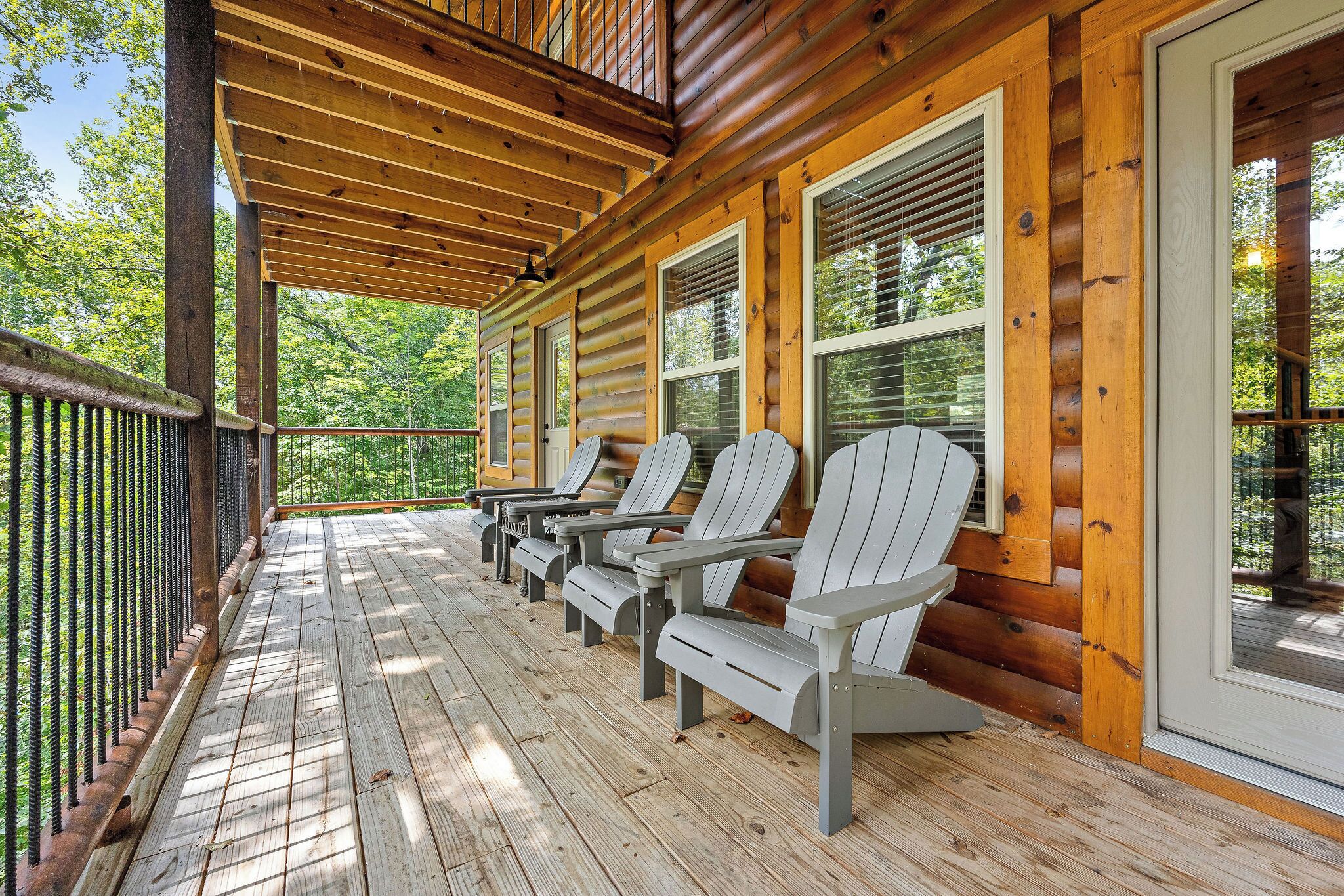 A wooden deck with Adirondack chairs and a wooden railing.