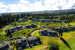 A residential area with multiple two-story houses, a swimming pool, and a hilly landscape in the background.