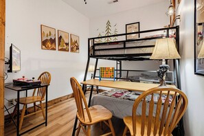 Un lit superposé avec un bureau et des chaises, une lampe et des œuvres d’art accrochées aux murs.