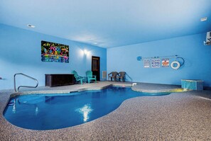 Un espace piscine avec un mur bleu, un panneau indiquant qu’une fête est organisée au bord de la piscine et un poste de surveillance pour les sauveteurs.