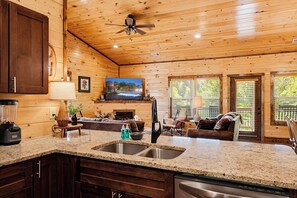 A cabin interior with a kitchen, dining area, and living room.