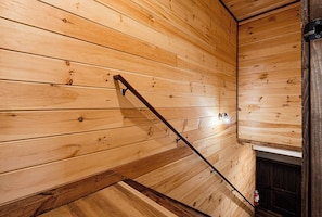 Een houten interieur met een trap en een wandlamp.