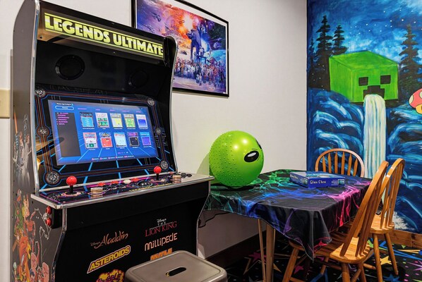 A gaming arcade with a selection of video games, a green exercise ball, and a table with a glass chess set.
