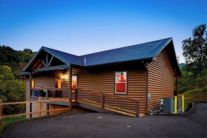 Une cabane en bois avec un toit en pente, une véranda couverte et une entrée clôturée.